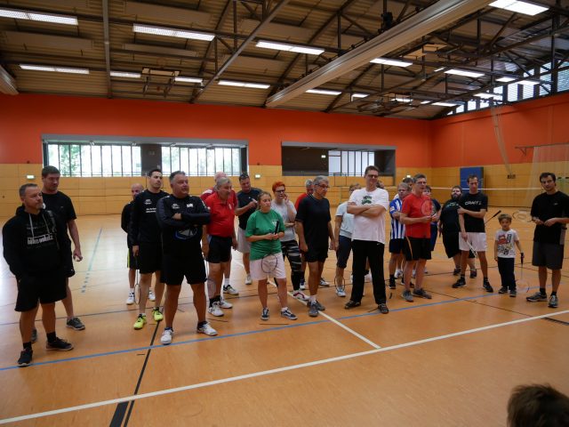 die sieben teilnehmende Mannschaften des BSG BA Neukölln Turnier der Abteilungen 2018 stehen in einer Sporthalle zwischen den aufgebauten Badminton-Feldern